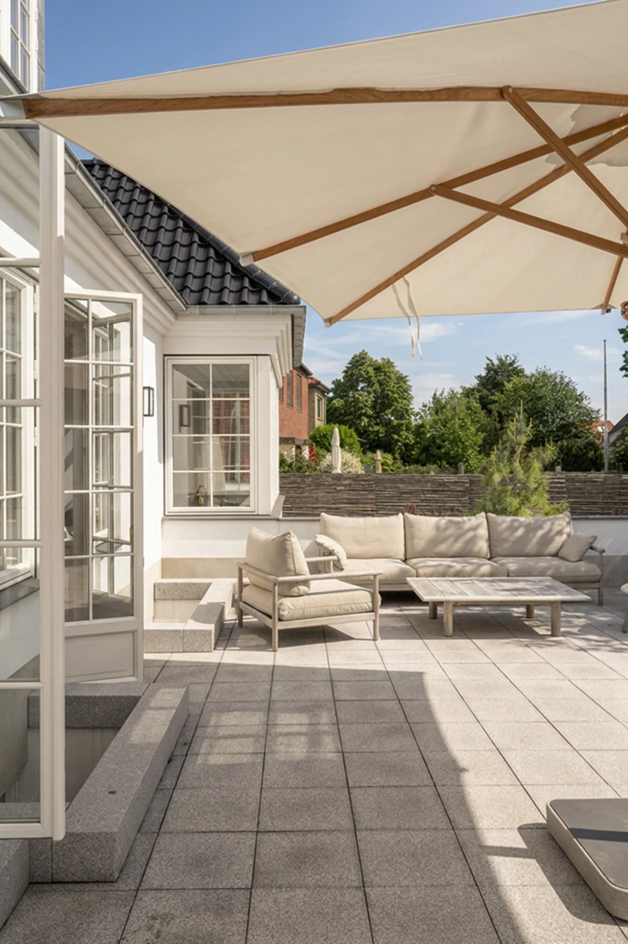Overdækket terrasse med loungemøbler og parasol